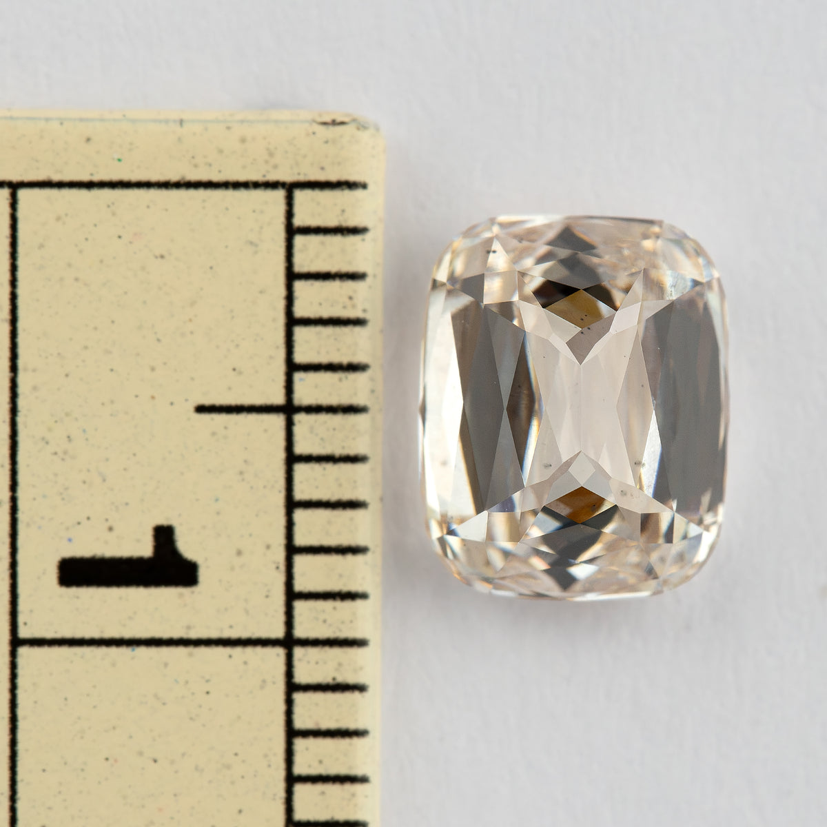 The diamond beside a millimetre ruler, providing a visual reference for its face-up dimensions.