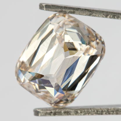 Pavilion-side view of the elongated cushion diamond held in tweezers, showing the back facet arrangement.