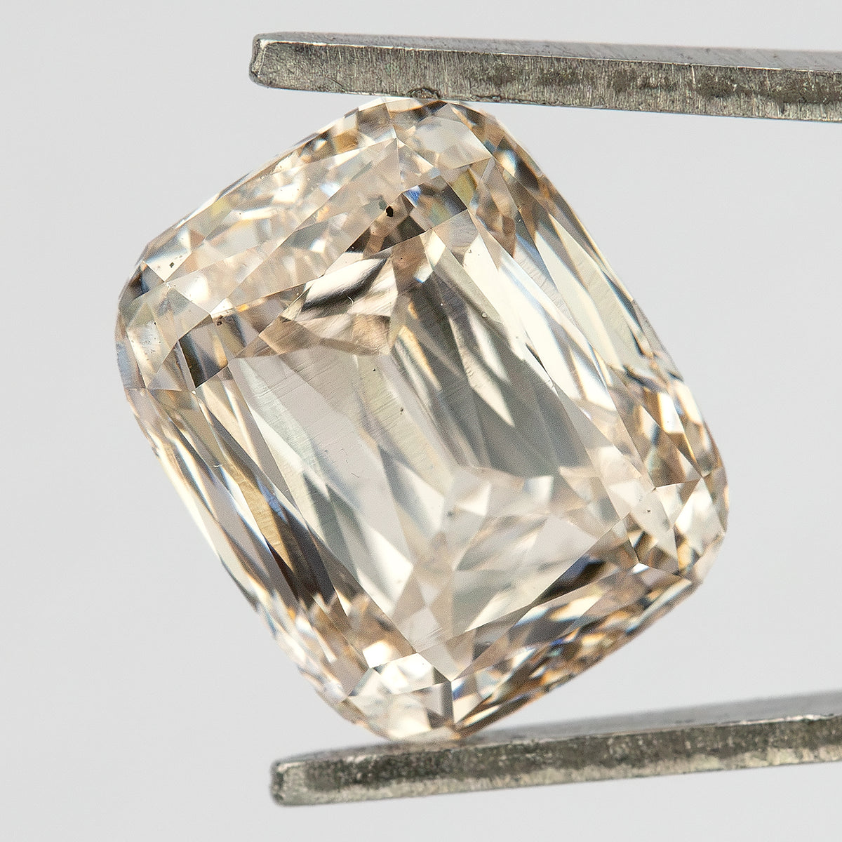 Steeper angled view of the diamond in tweezers, showing the rounded corners and modified-brilliant facet pattern.
