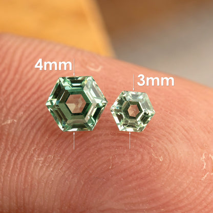 Two mint green hexagonal lab-grown sapphires on a fingertip, with labels identifying the 4mm and 3mm sizes.