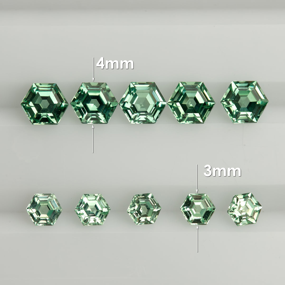 Two rows of mint green hexagonal lab-grown sapphires on a white tray, labelled 4mm above and 3mm below.