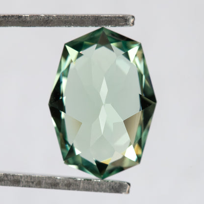 Pavilion and back view of the BLS111 mint green lab-grown sapphire in tweezers.