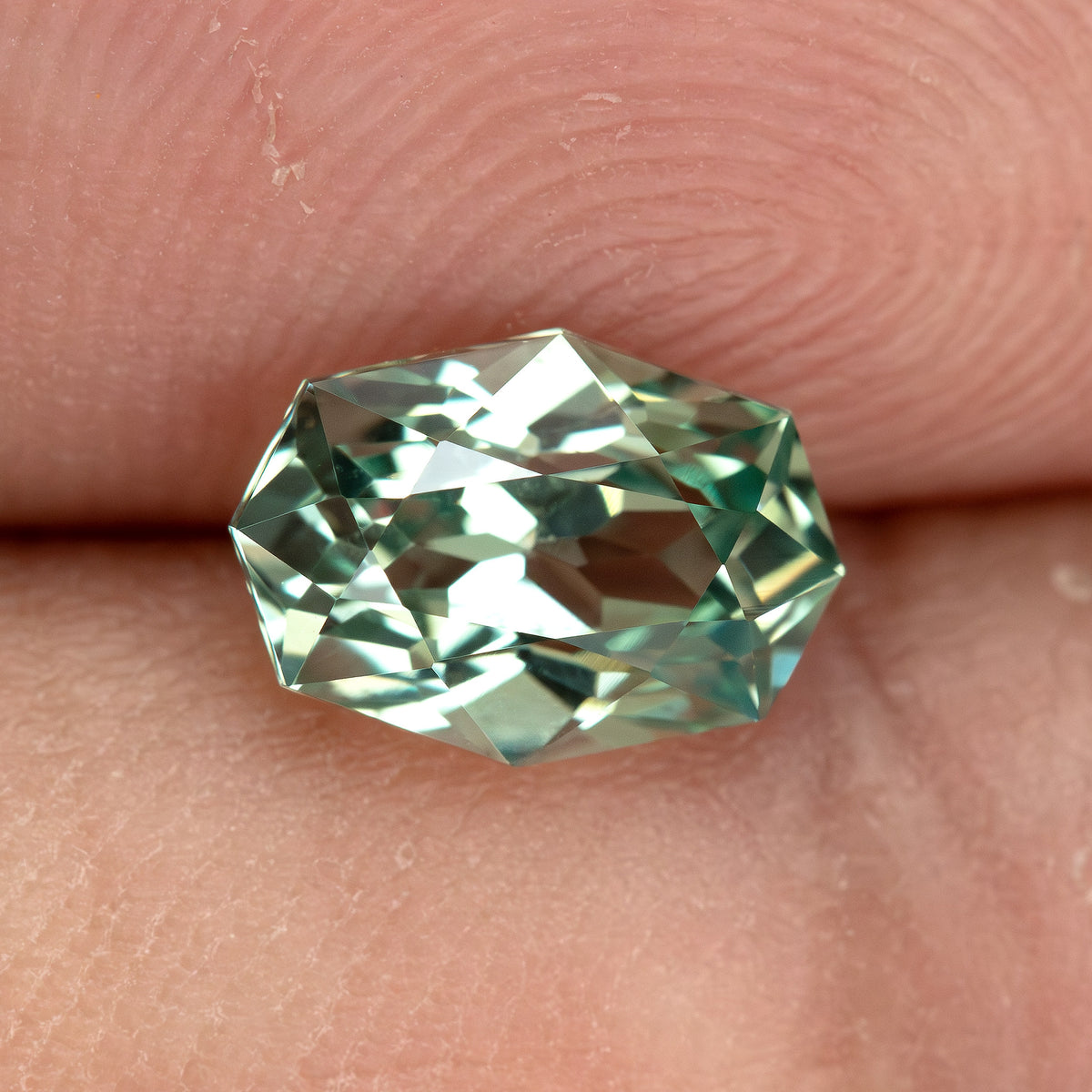 Second fingertip view of BLS111, showing its elongated outline and mint green reflections.