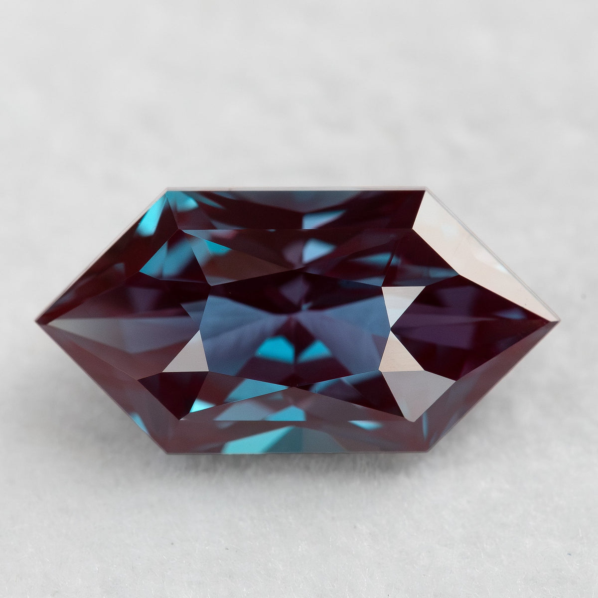 Face-up BLS112 lab-grown alexandrite with red-purple color and greenish-blue reflections.