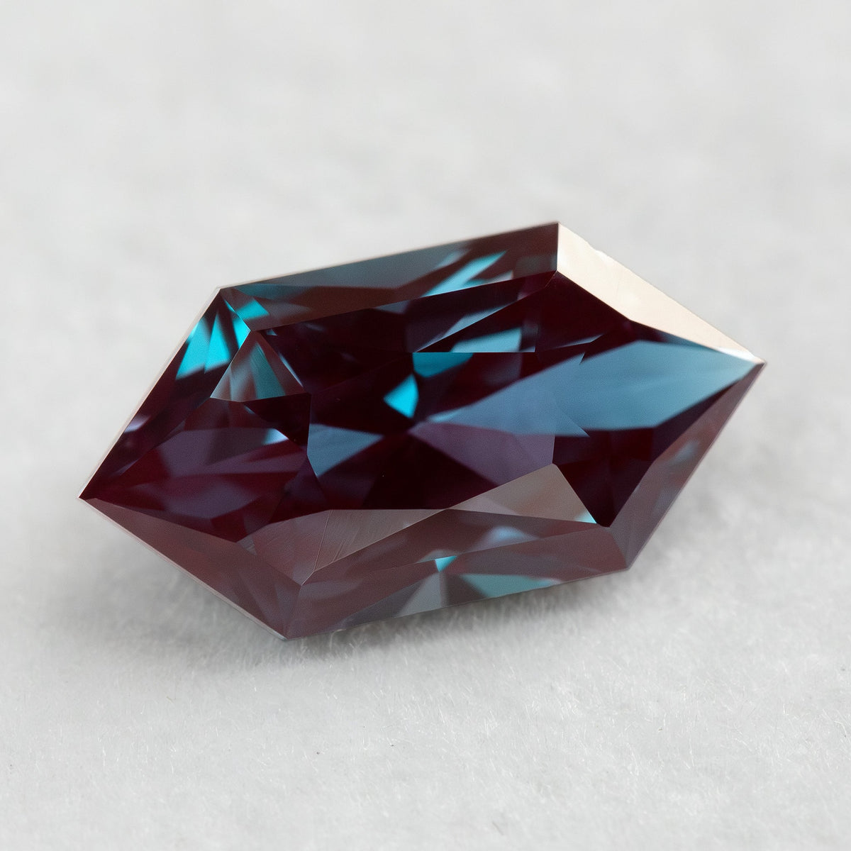 Alternate face-up view of the BLS112 lab-grown alexandrite, showing changes in red-purple and greenish-blue reflections.