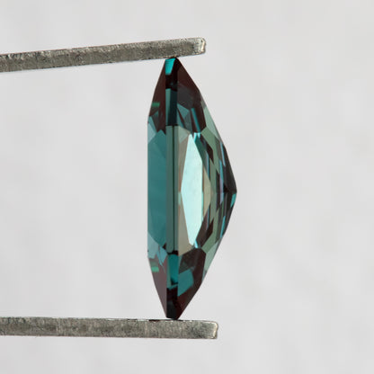 Side profile of BLS113 lab-grown alexandrite in tweezers, showing its crown, girdle and pavilion depth.