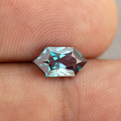 Alternate fingertip view of BLS113 showing its elongated geometric outline and mixed blue-green and reddish reflections.