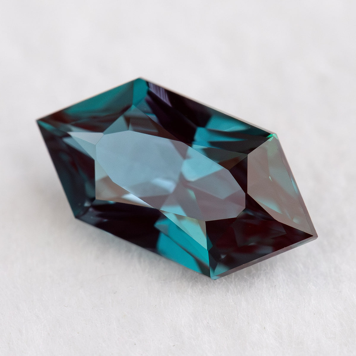 Alternate angled view of BLS113 lab-grown alexandrite, showing its geometric outline and color-changing reflections.