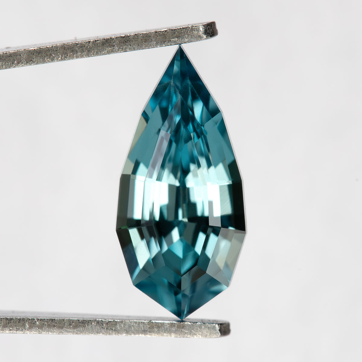 Front view of one teal blue-green BLS114 lab-grown sapphire in an elongated pear shape.