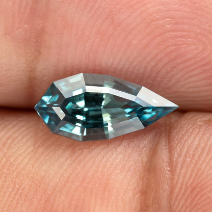 Hand-held daylight view of one BLS114 teal blue-green lab-grown sapphire.