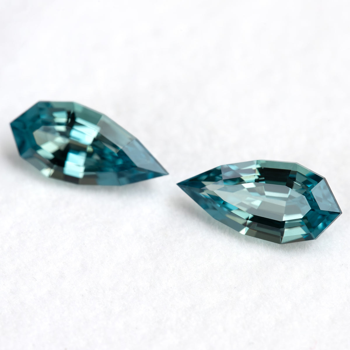 Close view of the paired BLS114 elongated pear sapphires and their blue-green color balance.
