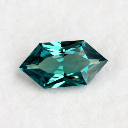 Face-up BLS115 teal green lab-grown sapphire on white, showing its Dutch Marquise Hexagon outline and geometric facets.