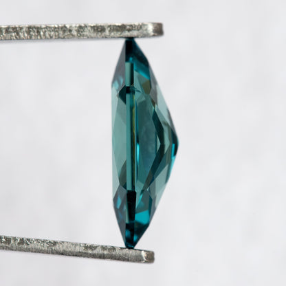 Side profile of BLS115 lab-grown sapphire in tweezers, showing its crown, girdle and pavilion depth.