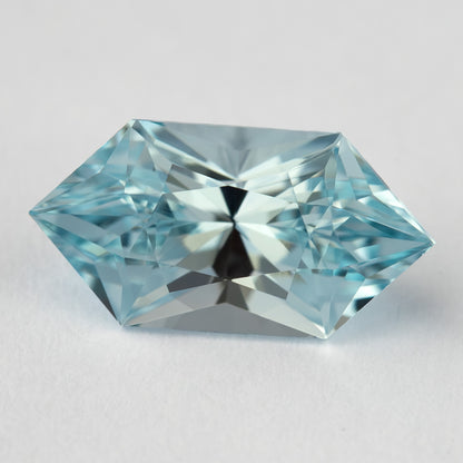 Horizontal face-up view of an aquamarine-blue lab-grown sapphire, showing its pointed ends and alternating light and dark facets.