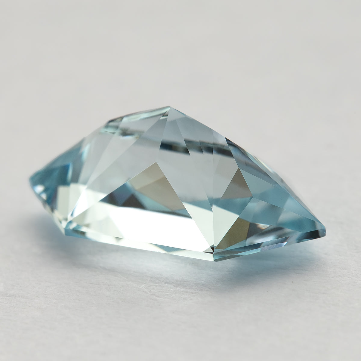 Low angled view of the pale-blue lab-grown sapphire on a flat surface, showing its raised profile.