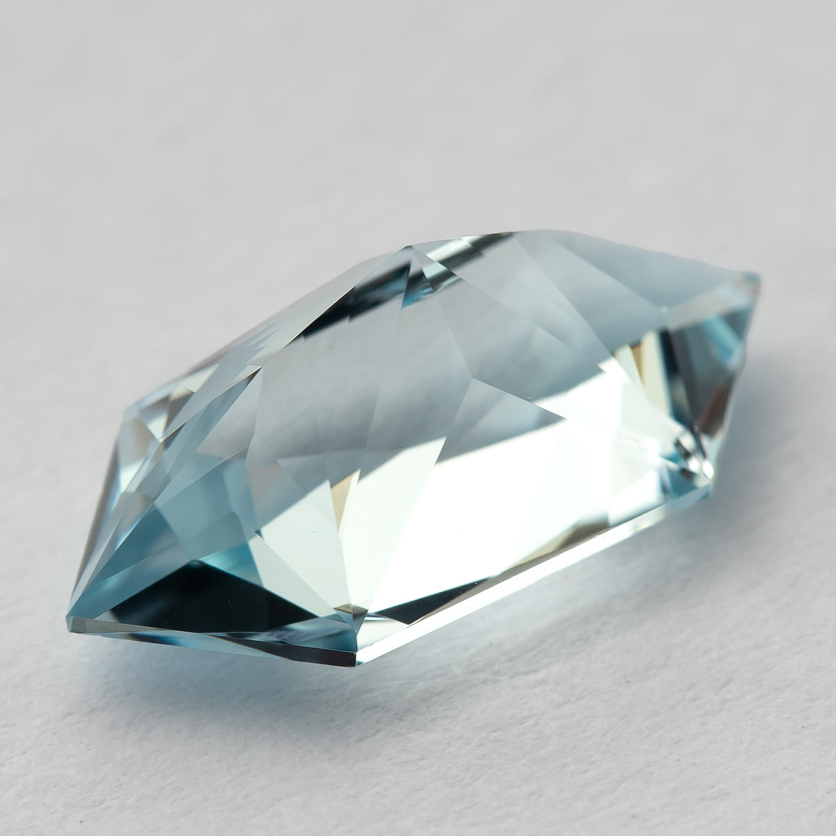 Oblique view of the aquamarine-blue lab-grown sapphire, showing the sloping facets and outline.