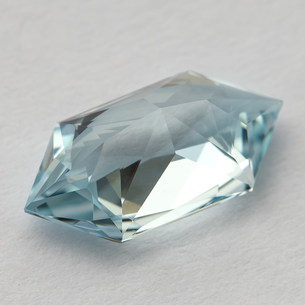 Tilted view of the pale-blue lab-grown sapphire, showing the depth and angular facets.