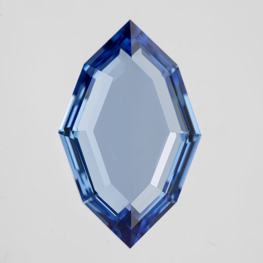 Blue portrait-cut lab-grown sapphire viewed face-up vertically on white, with a broad transparent table and stepped hexagonal outline.
