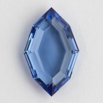 Pavilion-side view of the blue hexagonal portrait-cut sapphire on white, showing broad pale facets.