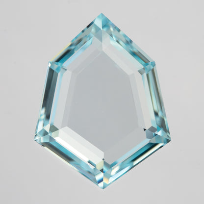 Aquamarine-blue shield portrait-cut lab-grown sapphire, face-up on white with a broad transparent table and narrow step facets.