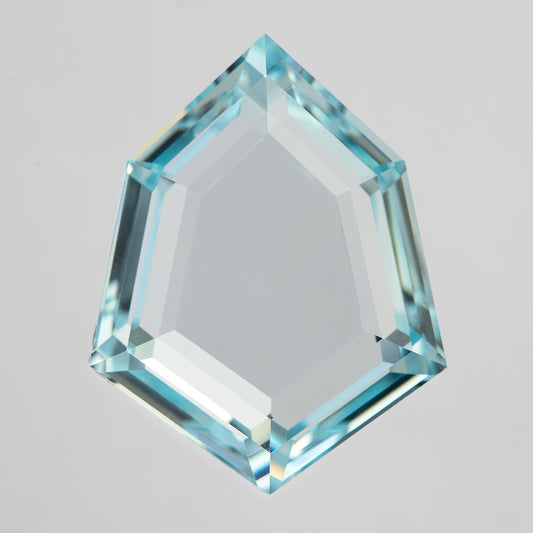 Aquamarine-blue shield portrait-cut lab-grown sapphire, face-up on white with a broad transparent table and narrow step facets.