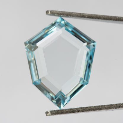 Aquamarine-blue shield-shaped lab-grown sapphire shown at an angle from the pavilion side. View 12.