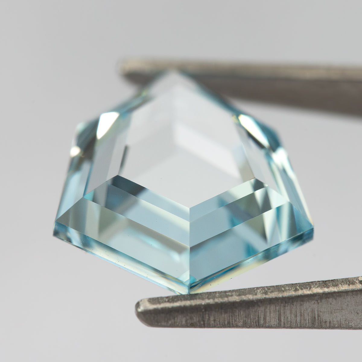 Aquamarine-blue shield-shaped lab-grown sapphire viewed from the side, showing crown and pavilion depth. View 17.