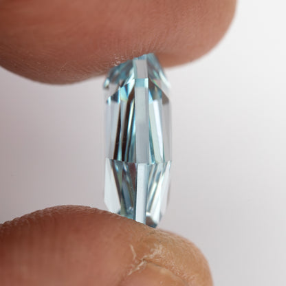 Aquamarine-blue shield-shaped lab-grown sapphire viewed from the side, showing crown and pavilion depth. View 13.