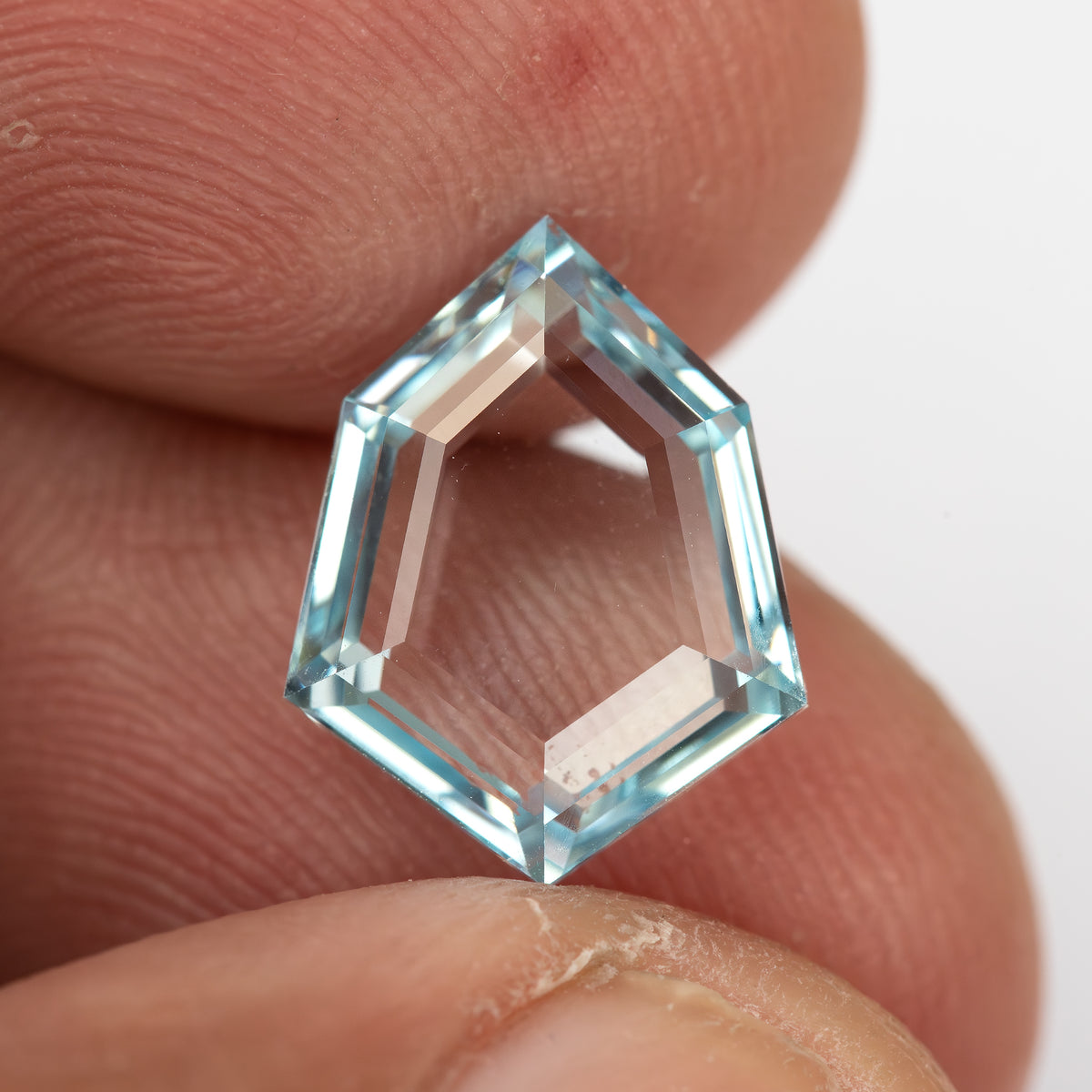 Aquamarine-blue shield-shaped lab-grown sapphire shown at an angle from the pavilion side. View 18.