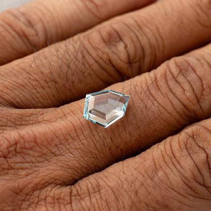 Aquamarine-blue shield-shaped lab-grown sapphire shown against a hand for scale. View 19.
