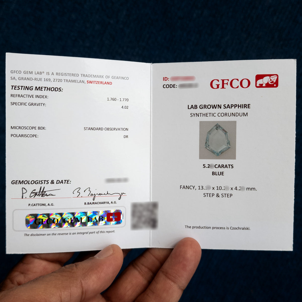 Photographed GFCO reference report identifying lab-grown sapphire, synthetic corundum, blue color, fancy shape, step facets and Czochralski growth; identifying numbers and some measurements are masked.