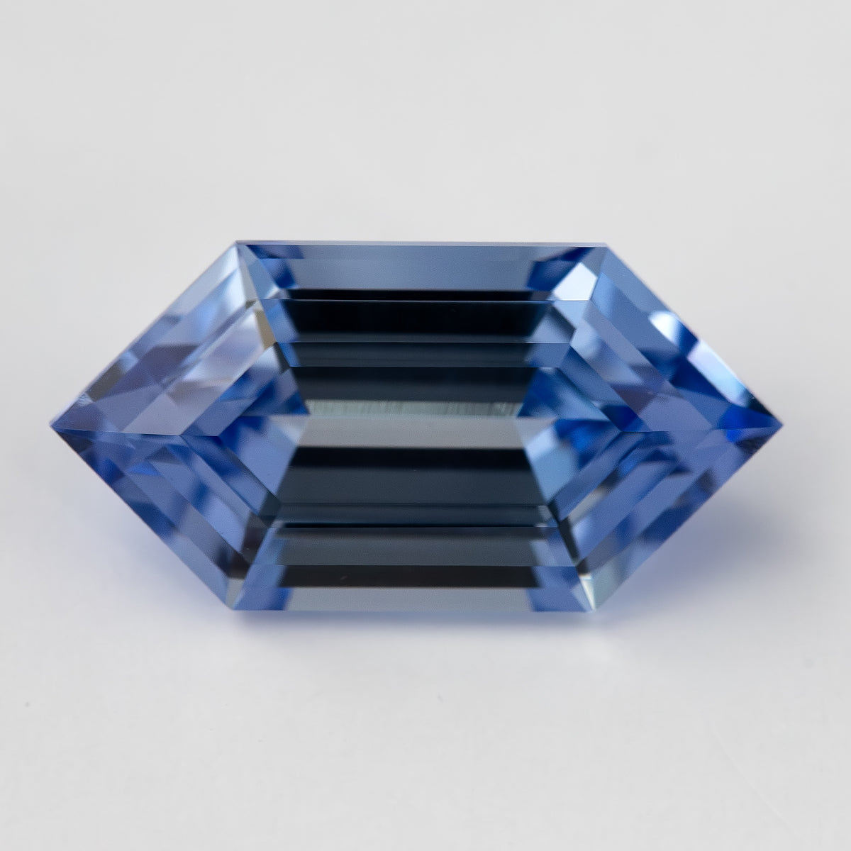 The long hexagon blue lab-grown sapphire face-up, with dark parallel reflections through its center.