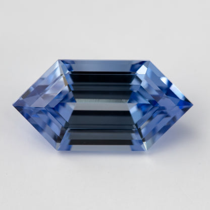 The long hexagon blue lab-grown sapphire face-up, with dark parallel reflections through its center.