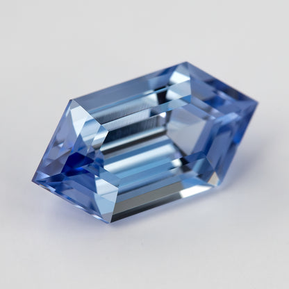 Closer angled view of the blue long-hexagon lab-grown sapphire, showing alternating pale and dark step reflections.
