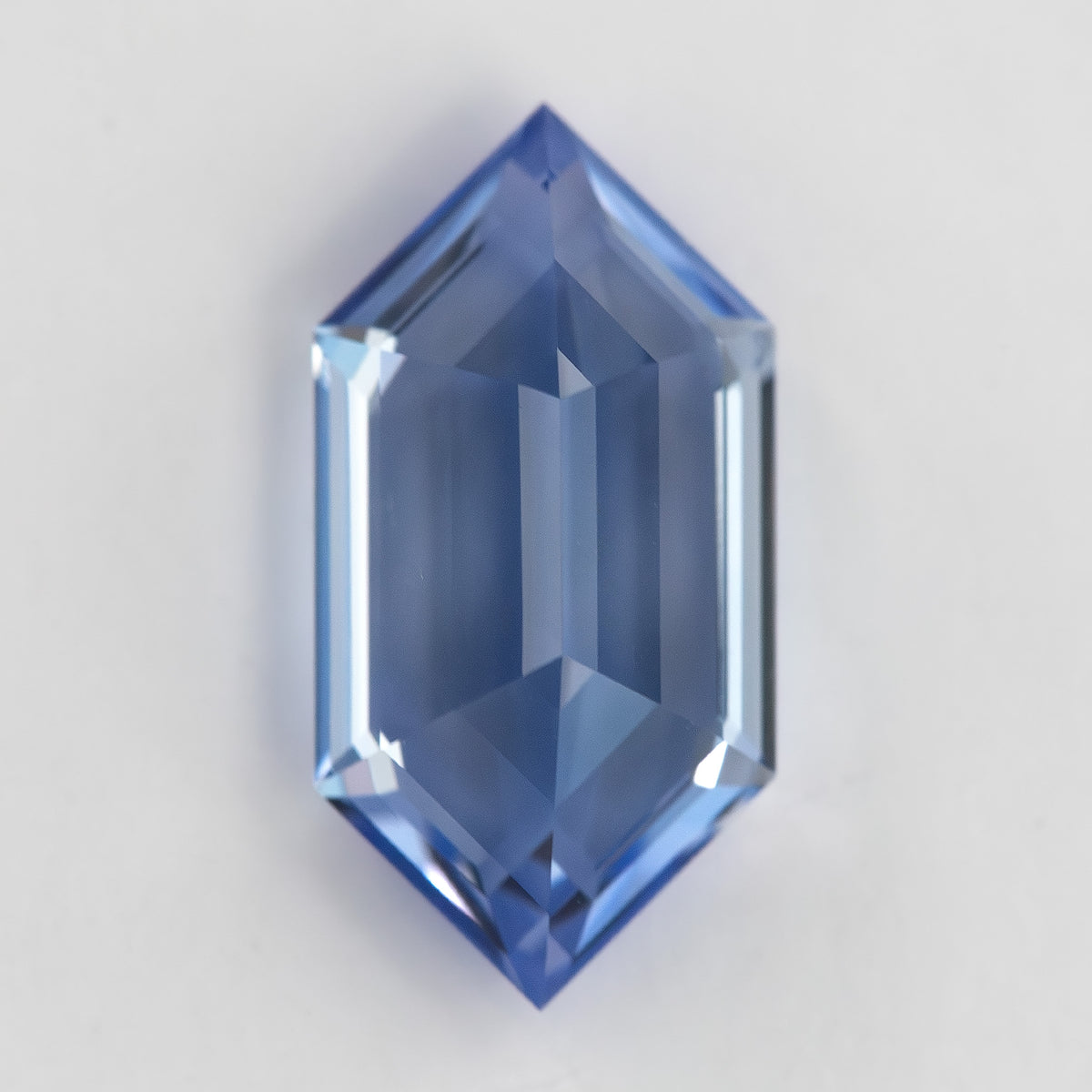 Reverse view of the blue elongated-hexagon sapphire, with broad pale reflections through the underside.