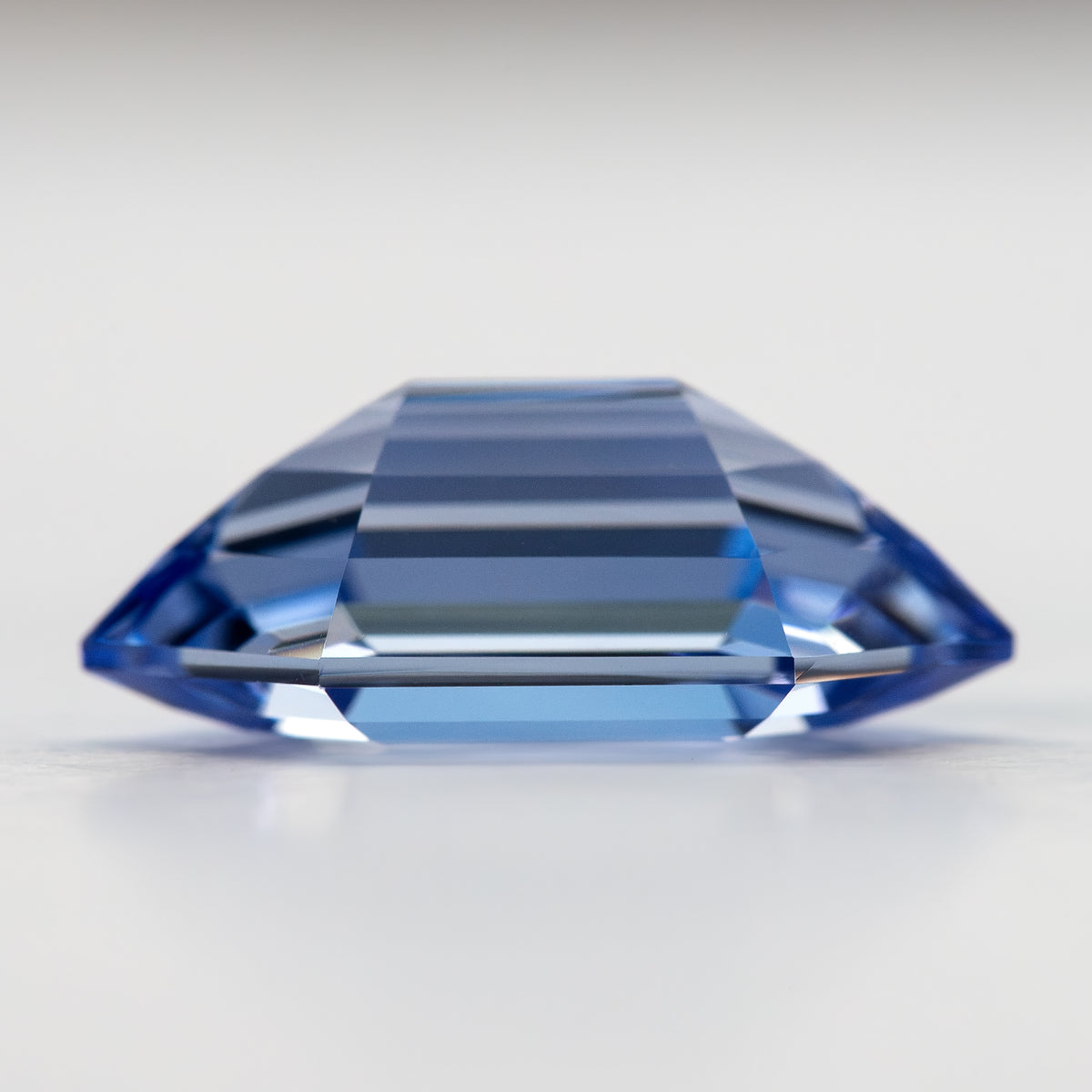 Low side profile of the blue long-hexagon sapphire, showing the crown and pavilion above and below the edge.