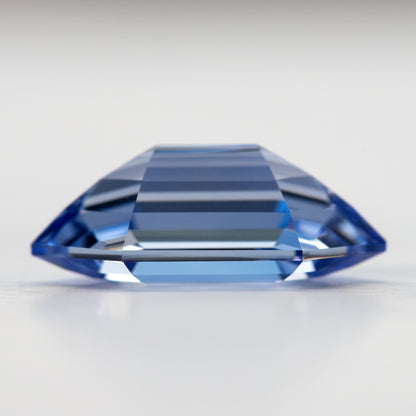 Low side profile of the blue long-hexagon sapphire, showing the crown and pavilion above and below the edge.