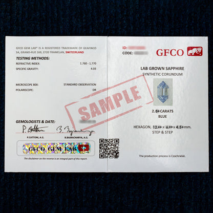 GFCO report photograph marked SAMPLE for the blue lab-grown sapphire production, shown against dark fabric.