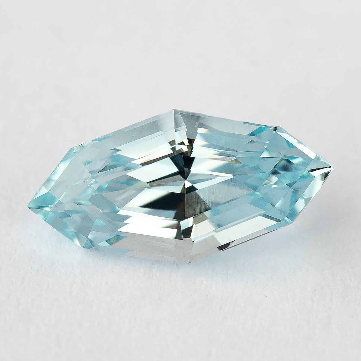A marquise-shaped, step-cut, light blue lab-grown sapphire centered on a white background.