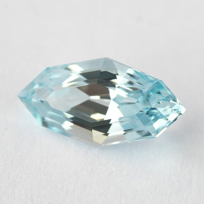 A marquise-shaped, step-cut, light blue lab-grown sapphire angled slightly on a white background.