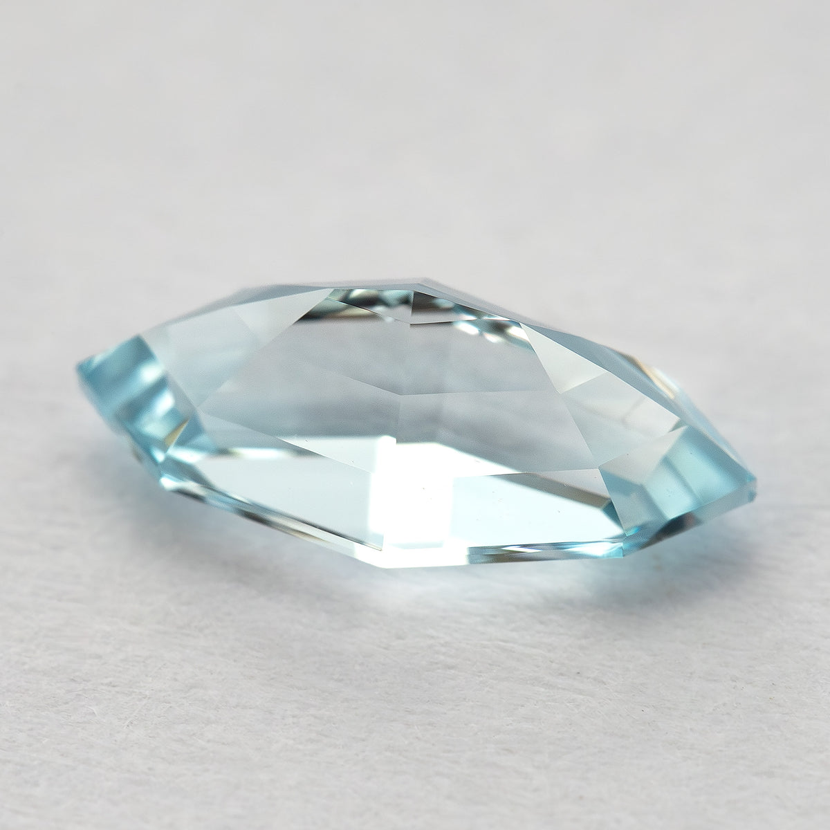 Oblique pavilion-side view of the light blue marquise step-cut lab-grown sapphire, with broad pale reverse facets.
