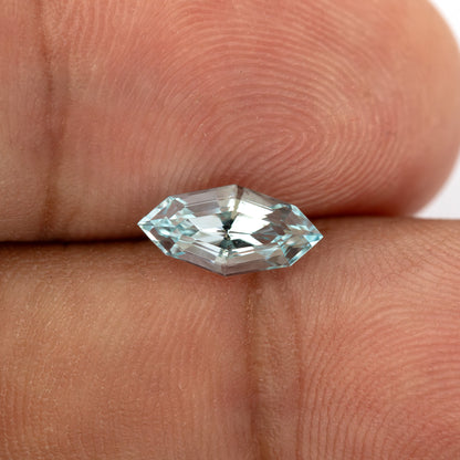 Light blue step-cut lab-grown sapphire resting on fingertips for scale.