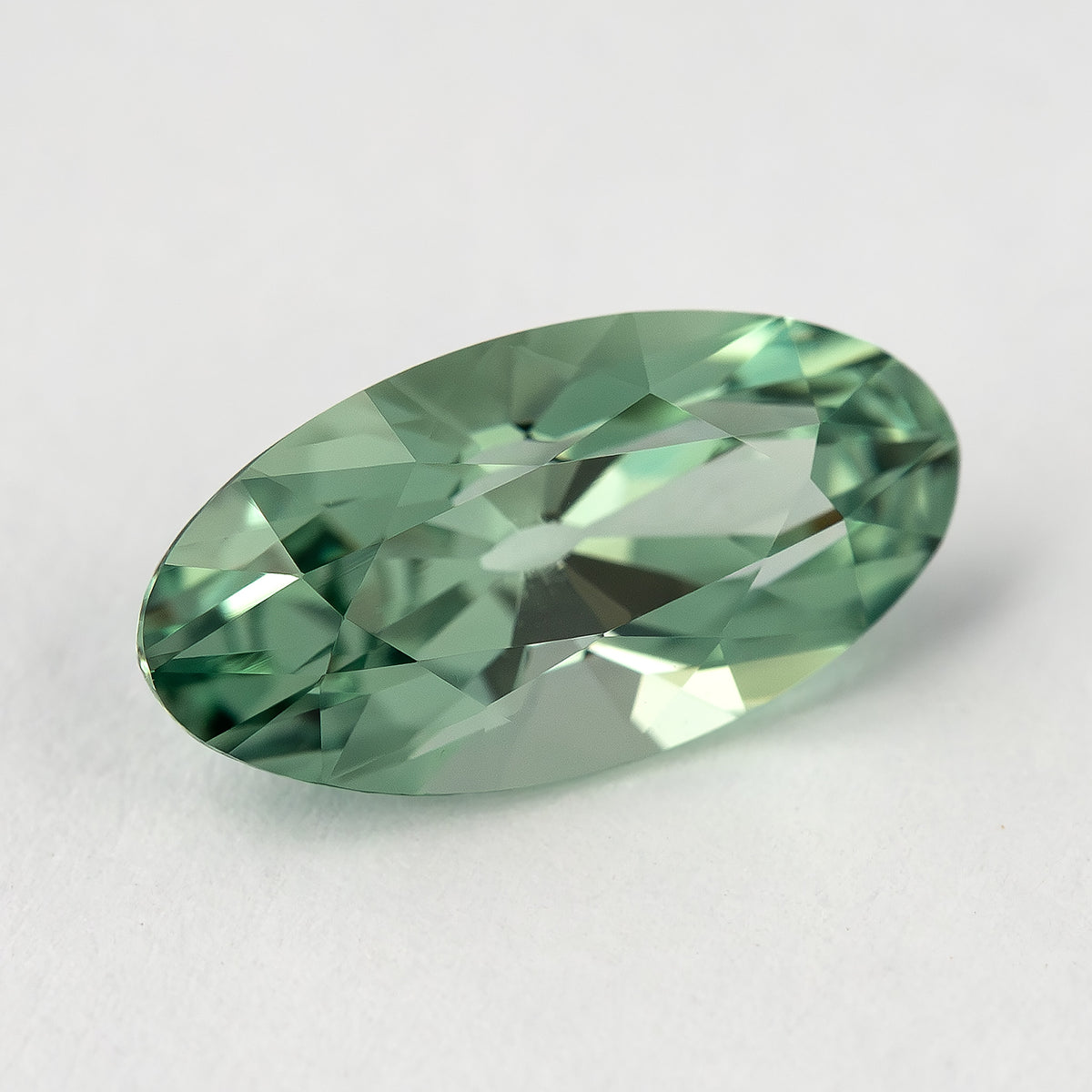 Diagonal crown view of the mint-green lab-grown sapphire, showing its curved sides and pointed ends.