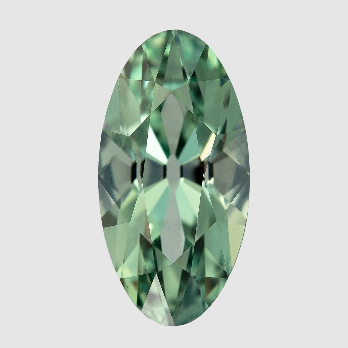 Mint-green lab-grown sapphire upright on a pale surface, showing the complete long outline and alternating facet reflections.
