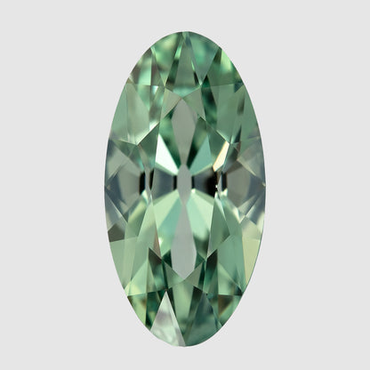 Mint-green lab-grown sapphire upright on a pale surface, showing the complete long outline and alternating facet reflections.