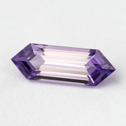 Lavender lab-grown sapphire on a pale background, showing its elongated shape and light violet facet reflections.