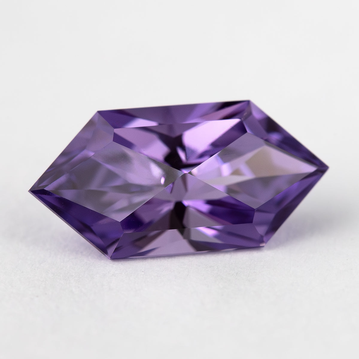 Violet elongated hexagon sapphire tilted to show reflections across its face-up facets.