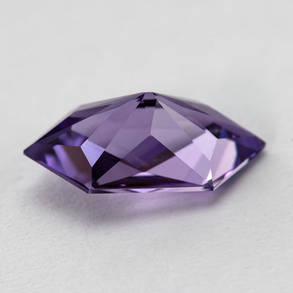 Angled reverse view of the violet lab-grown sapphire on a light background.