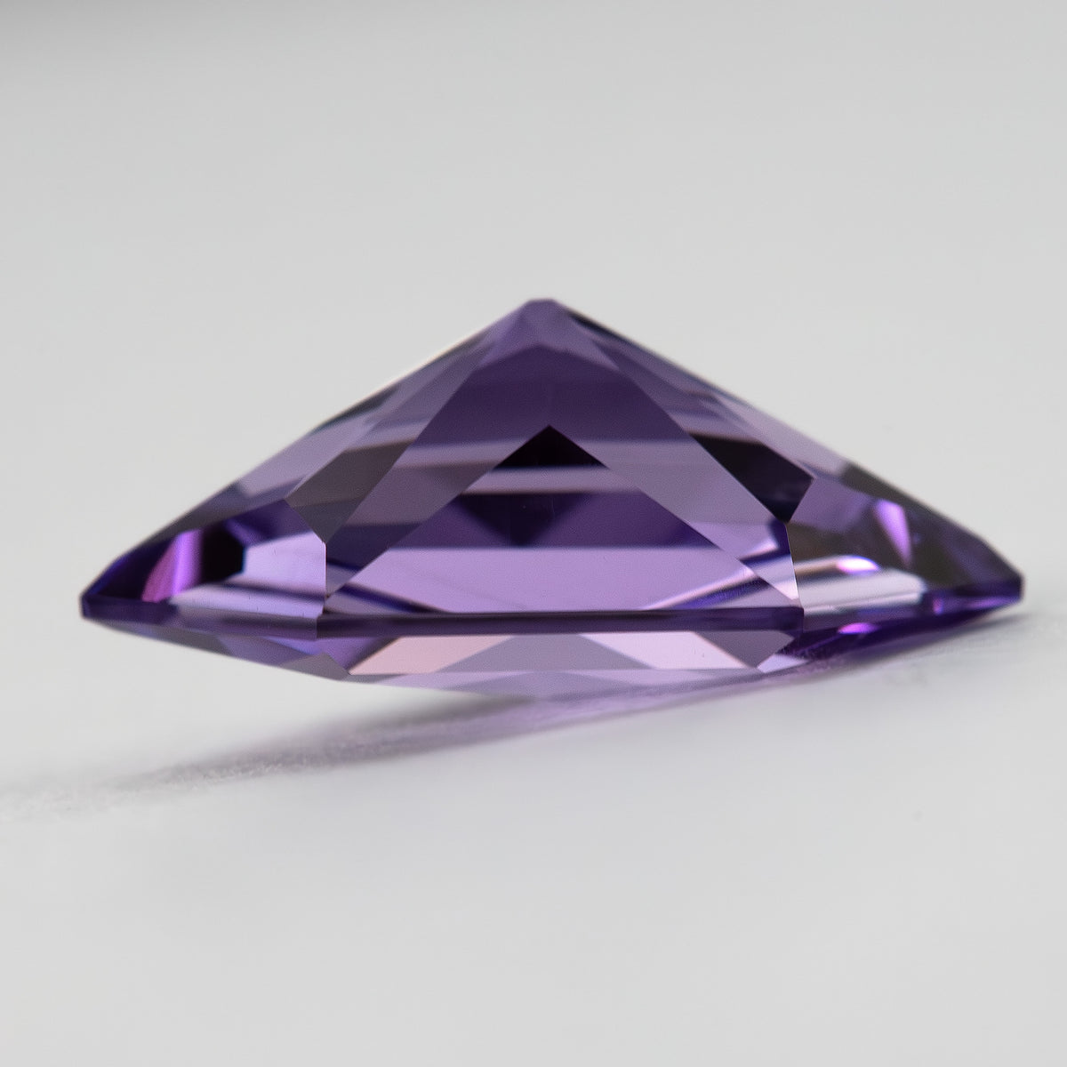 Oblique profile of the violet lab-grown sapphire showing depth and pavilion faceting.