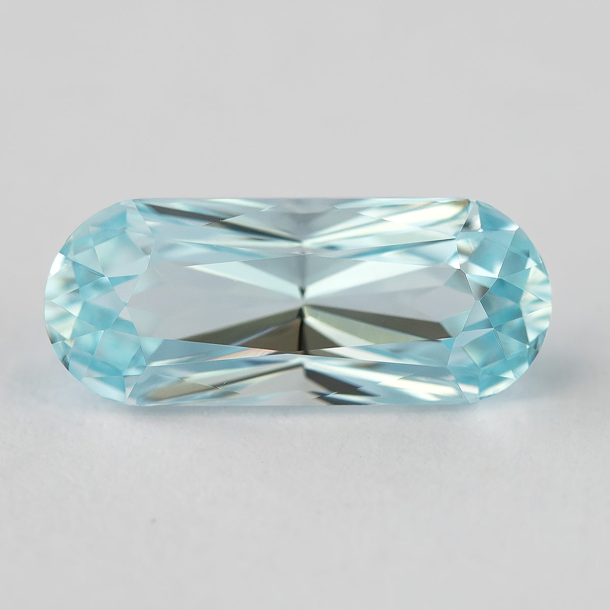 Elongated light blue sapphire with bright reflections along the center facets.